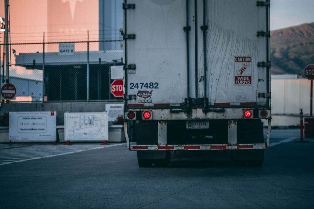 pexels-photo-2449454 Semi truck parked at a loading dock with visible caution signs and industrial surroundings.
